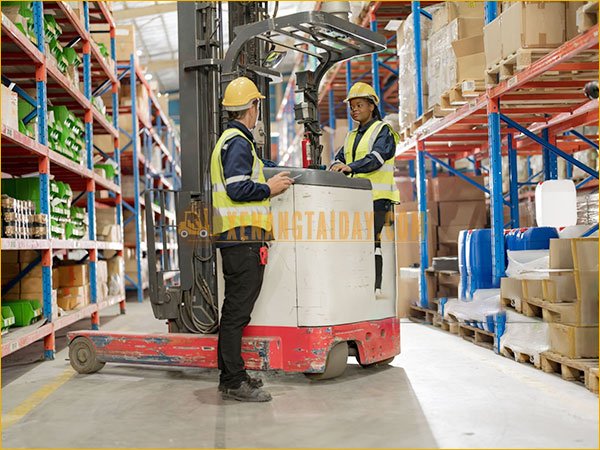 Xe nâng điện đứng lái hoạt động trong kho có mặt sàn bằng phẳng